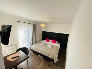 a bedroom with a bed with red pillows and a desk at Casa Bozi in Utvin