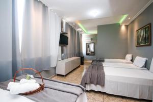 a hotel room with two beds and a couch at Pousada Maresia Costa Azul in Rio das Ostras