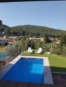 a swimming pool with two lounge chairs and a lawn at Casa La Peguera in La Parra
