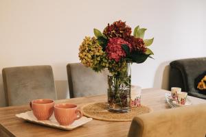 a vase of flowers sitting on a table with two cups at Apartman Valerija in Doboj