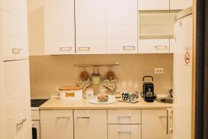 a kitchen with white cabinets and a plate of food at Apartman Valerija in Doboj +11 photos