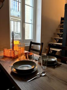 a wooden table with two plates and glasses on it at Studio industriel, mezzanine, rénové, central 201 in Saint-Étienne +21 photos