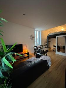 a living room with a black couch and a table at Studio industriel, mezzanine, rénové, central 201 in Saint-Étienne