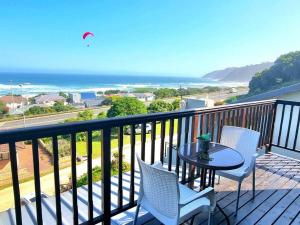 a balcony with a table and chairs and the ocean at Sea La Vie Beach House in Wilderness