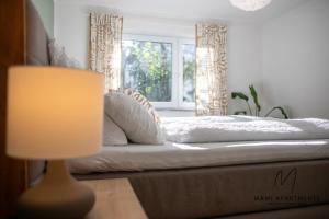 a bedroom with a bed with a lamp and a window at MaMi Apartments - TerraVista in Pliezhausen