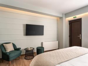 a bedroom with a bed and a chair and a tv at Anerada Hotel in Kalavrita