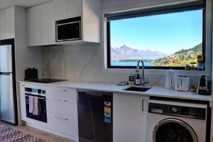 a kitchen with a sink and a washing machine at Relax on Snowy Place in Queenstown +7 photos