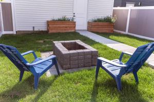 two blue chairs and a fire pit in a yard at Modern Retreat, AirCon, Backyard, Near DT & WEM in Edmonton