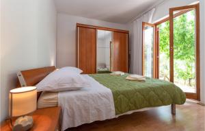 a bedroom with a bed with a green blanket and a window at 2 Bedroom Amazing Home In Pridraga in Pridraga