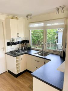 a kitchen with white cabinets and a black counter top at Familiehuis Zeegserduinen in Zeegse +20 photos