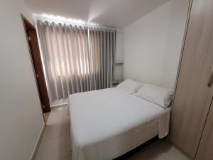 ein kleines Schlafzimmer mit einem weißen Bett und einem Fenster in der Unterkunft Cittá Por do sol Familia Shopping e Parque in Brasilia