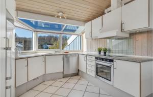 a kitchen with white cabinets and a large window at Holiday Home Kystvej Bjert Ix in Binderup Strand