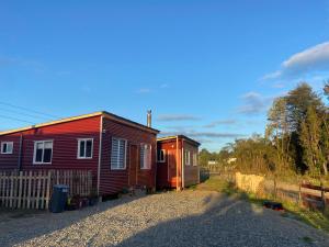 two houses sitting next to each other on a gravel road at Cabaña la chilotita in Dalcahue