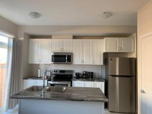 a kitchen with white cabinets and a stainless steel refrigerator at Brand new house in Ottawa