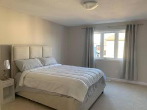 a white bedroom with a large bed and a window at Brand new house in Ottawa