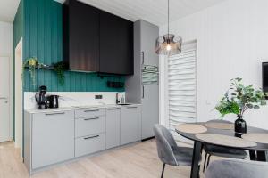 a kitchen with white cabinets and a table with chairs at Mano jūra Small rest house in Palanga
