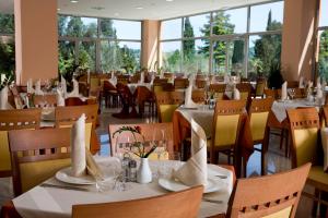 un ristorante con tavoli e sedie bianchi e finestre di Bioenergy Resort Salinera Hotel a Strunjan