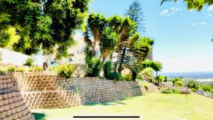 a brick retaining wall with trees and palm trees at Hotel Vibes Cape Town Plattekloof in Cape Town
