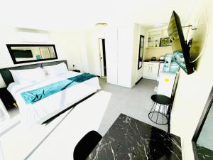 a white bedroom with a bed and a kitchen at Hotel Vibes Cape Town Plattekloof in Cape Town