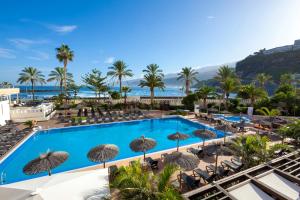 Blick auf den Pool in einem Resort mit Stühlen und Sonnenschirmen in der Unterkunft Sol Costa Atlantis Tenerife in Puerto de la Cruz