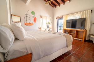 a bedroom with a bed and a flat screen tv at Hanna Hotel Boutique in Valle de Bravo