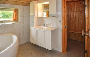 a bathroom with a sink and a tub and a toilet at Holiday Home Hindbærvangen Oksbøl V in Oksbøl