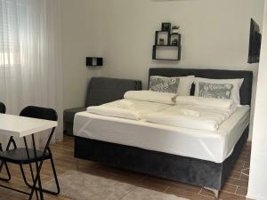 una cama en una habitación con una silla y un sofá en Apartmani Zilic, en Mostar