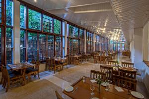 a restaurant with tables and chairs and large windows at Villagio Embu Resort & Convention in Embu