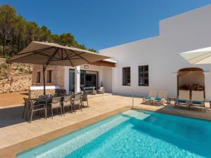 a villa with a swimming pool and an umbrella at Holiday home with children play area in Santa Eularia des Riu