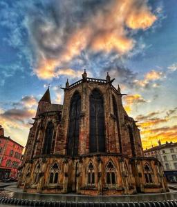 an old church with a cloudy sky behind it at La Terrasse Urbaine Epinal in Épinal