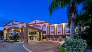 a building with a palm tree in front of it at Best Western Plus Ambassador Suites in Venice