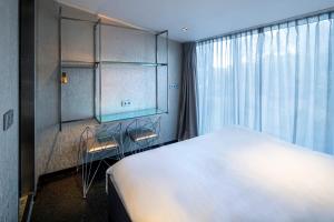 阿姆斯特尔芬Diamond Capsule Hotel Amsterdam South的卧室里有一张白色的大床和一扇窗户