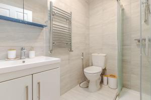 a bathroom with a toilet and a sink and a shower at Parkside Haven, Modern 2-Bed Flat with Ensuites, Free Parking & Self Check-In in Perivale