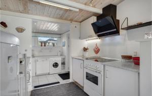 a kitchen with white appliances and a tv on the wall at Three-Bedroom Holiday Home In Sydals in Østerby +19 photos