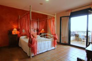 a bedroom with a canopy bed and a balcony at Hotel Rural Hojaranzos in Tejeda de Tiétar +22 photos