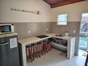 a kitchen with a counter with a stove and stools at Villa Bali Maresias Lofts in Maresias