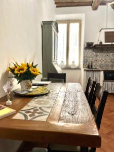 a wooden table with a vase of yellow flowers on it at Il Girasole Storico in Pitigliano +17 photos