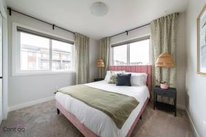 a bedroom with a large bed and two windows at The Nest, 3BR, AC, Near YEG Airport, King Bed! in Edmonton +52 photos