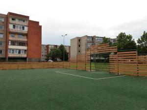 a tennis court with a fence in front of some buildings at Apartment with private entrance in Šilutė