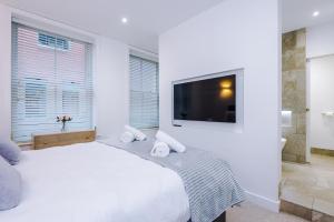 a white bedroom with a large bed and a flat screen tv at Stylish 3-Bed Central Stay - Roof Terrace & Parking in Manchester
