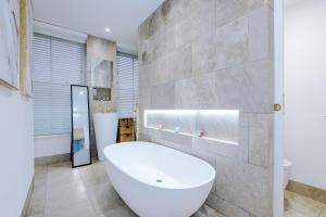 a bathroom with a large white tub and a stone wall at Stylish 3-Bed Central Stay - Roof Terrace & Parking in Manchester