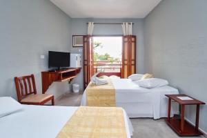 a room with three beds and a desk and a television at Pousada Mar Azul in Ubatuba +44 photos