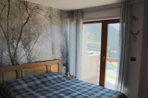 a bedroom with a bed and a window at Bilocale I cervi a pochi passi dalle piste con vista Mondolè in Prato Nevoso