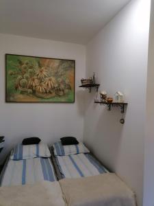 a bedroom with two beds and a painting on the wall at Luna Vendégház in Ipolyvece