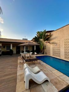 einen Pool mit einem weißen Stuhl neben einem Haus in der Unterkunft Porto das Dunas Casa Temporada Estilo e Conforto 2 in Aquiraz