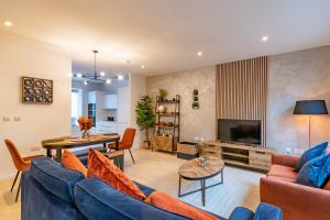 a living room with a blue couch and a television at Modern 5 Bedroom Town House with off St Parking in Bristol