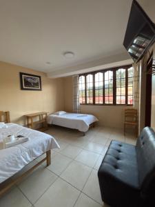 a bedroom with two beds and a couch and windows at Hospedaje CRUZ Oxapampa in Oxapampa