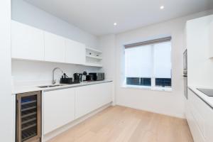 a white kitchen with a sink and a window at Modern 5 Bedroom Town House with off St Parking in Bristol +29 photos