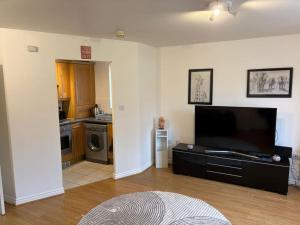 a living room with a flat screen tv and a kitchen at Stylish 1 Bed Apartment, Kings Heath, Birmingham in Birmingham