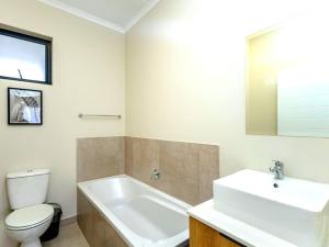 a bathroom with a white tub and a toilet and a sink at Urban Retreat in Midrand +2 photos